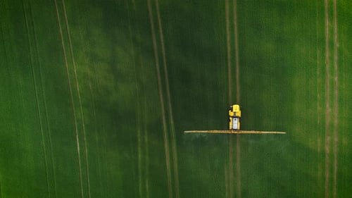 Tractor Sprays Crops on Rural Green Field