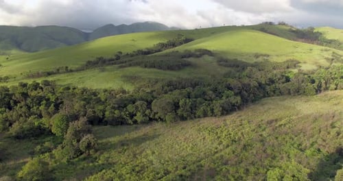 4k aerial drone footage flying over lush green forest hills on a beautiful day.