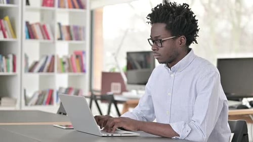 Young Adult Works on Laptop in Home Office