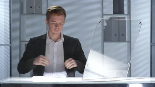 Kaukasischer Geschäftsmann tippt auf transparentem Computer im futuristischen Büro