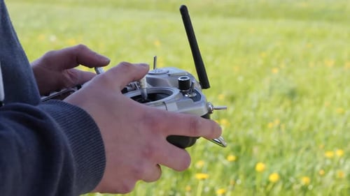 Side profile of caucasian hands using a radio remote control outdoors in a field
