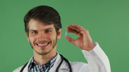 Cheerful Male Doctor Smiling Holding Blue Pill on Green Background 1080p