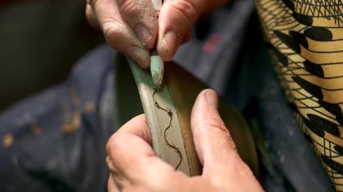 Potter Painting on Bowl in Pottery Workshop.