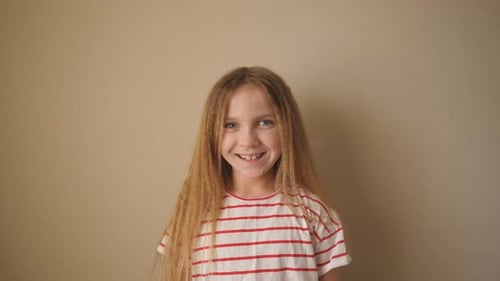 Kleines lächelndes Mädchen mit blonden Haaren, das in die Kamera schaut Nahaufnahme der Emotionen eines schönen Kindes