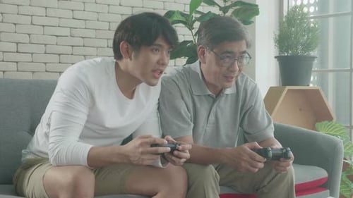 Father and Son Playing Video Games Together at Home