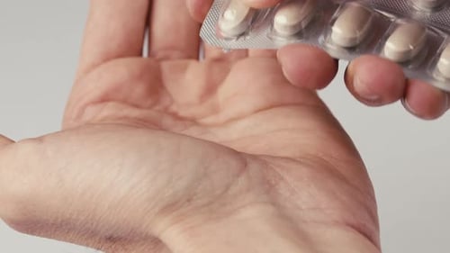 Händeschütteln eines Mannes, der zu Hause eine Pillenkapsel aus der Schachtel nimmt
