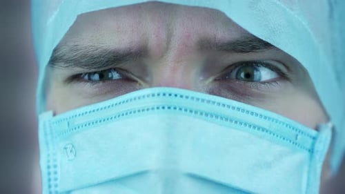 Intense Eyes of Young Doctor in Surgical Cap, Mask
