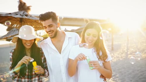 Young Adults Blowing Bubbles on Sunny Beach