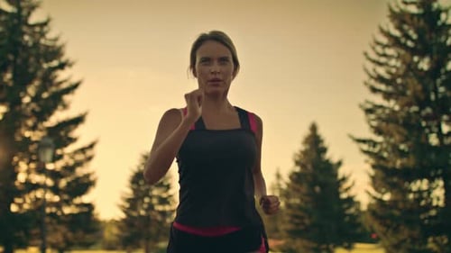 Young Woman Runner Running in Park at Sunset