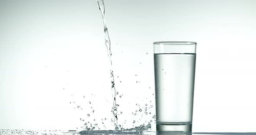 900037 Se vierte agua cerca del vidrio sobre un fondo blanco, Cámara lenta 4K