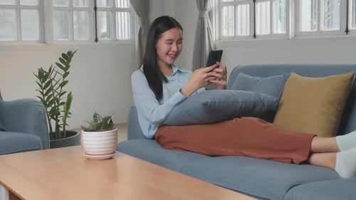 Smiling Woman Using Smartphone Relaxing on Couch