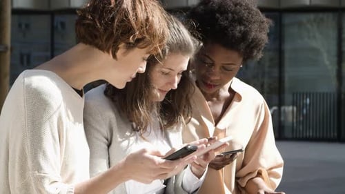 Three Women with Smartphones Standing on Street