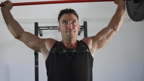 Fit kaukasischer Mann beim Training, Trainieren, Gewichtheben im Fitnessstudio