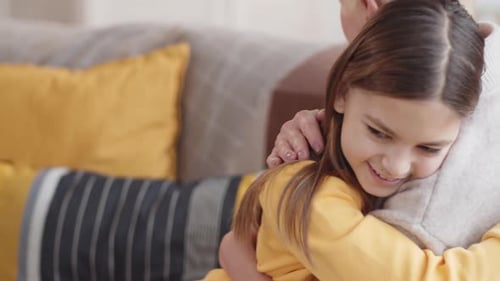 Girl Hugs her Grandmother on the Sofa