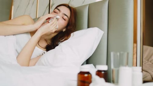 Woman in Bed Blowing Nose with Tissue