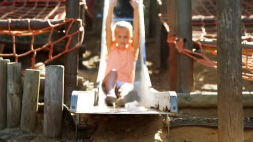 Schoolgirl sliding on slide in school playground