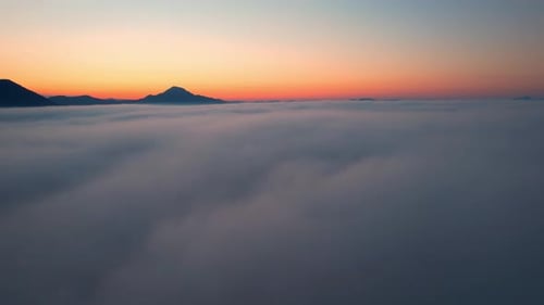 4K Aerial view flying in fog. the sun is hidden behind the clouds at sunset fog.