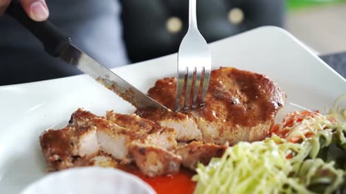 Close up of hand cutting a pork steak