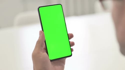 Man Looking at Smartphone with Green Chroma Screen