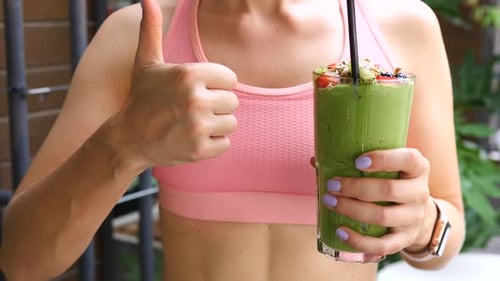 Sports Woman Holding Green Vegan Smoothie And Showing Thumbs Up. Healthy Lifestyle