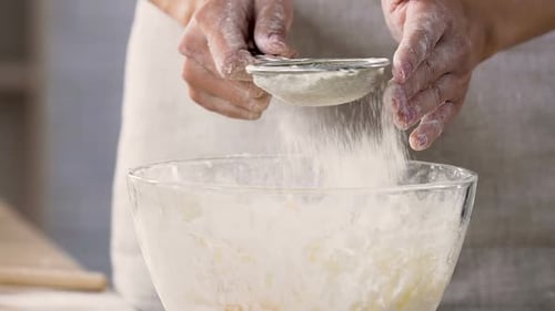 Woman Sifting Flour Into Mixing Bowl for Dough