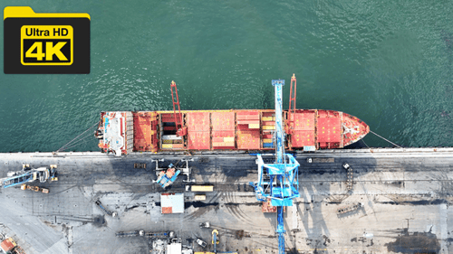 Vollständige Luftaufnahme von Frachtern, Containern und anstellenden Lastwagen, die im Hafen entladen und beladen werden