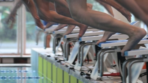 Мужчины-пловцы начинают со стартового стола в бассейне крупным планом. Замедленная съемка.