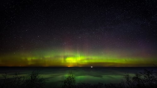 Замедленная
съемка. Живописное море под темным звездным небом с северным сиянием
.