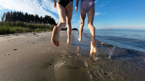 Two little girls run along the sea sandy shore. Slow motion.