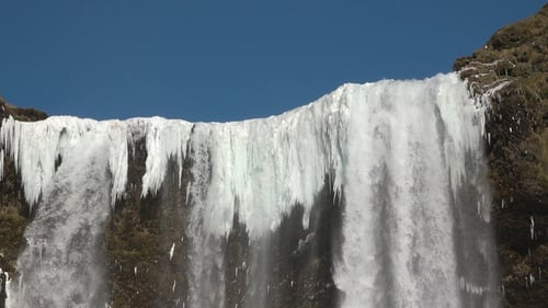 Island. Nahaufnahme des gefrorenen Wasserfalls mit eisigen Felsen. Winterliche Naturlandschaft mit Schnee und Eis.