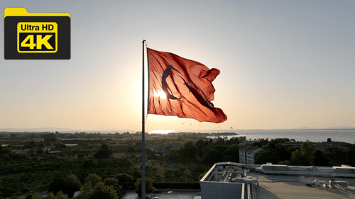 Aerial shot of waving turkish flag on a sunny day with the sun shining behind it