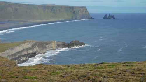 Beach cost, majestic top view on big rock formations cliff, foam waves, black sand beach in Iceland.
