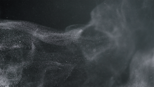 Dust particles rise into the air and swirl on a black background slow motion
