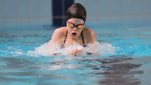 Swimmer girl swims breaststroke swimming style in the pool. Slow motion.