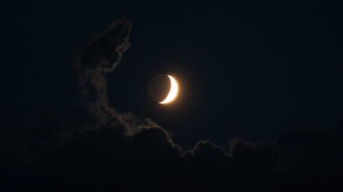 Bright Crescent Moon Shining Behind Fluffy Clouds