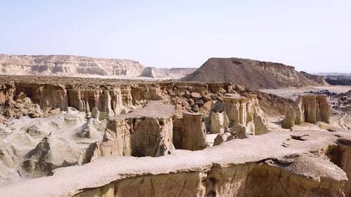 Explore a vast desert landscape with unique rock formations and distant hills during midday