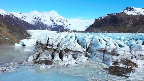 Landscape of an Icelandic glacier, featuring towering ice formations, a glacial lake, and mountains