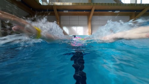 Une nageuse nage comme un papillon dans la piscine. Ralenti.