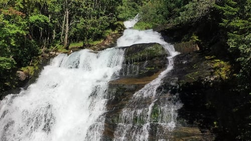 A breathtaking waterfall cascades down rocky cliffs surrounded by lush greenery
