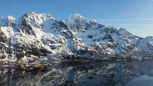 Mountains and fjords of Norway. Snow covered mountain range on coastline in winter. Aerial view.