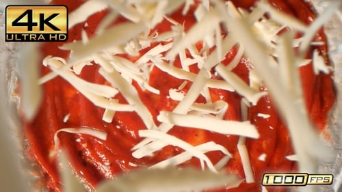 Pizza Crust With Tomato Sauce Sprinkled With Grated Cheese in Macro and Slow Motion - Table Top View