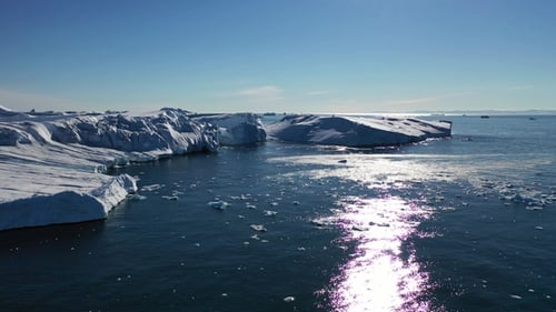 Arctic landscape at global warming problem. Icebergs melt at turquoise ocean bay. Ice drone shot.