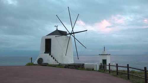 Windmill and Lighthouse on the Coast at Sunrise