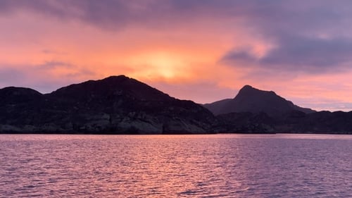 Sunset over mountains at a serene sea in a tranquil setting