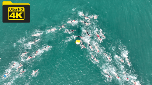 Aerial view from a drone of swimming athletes and swimmers competing in the sea