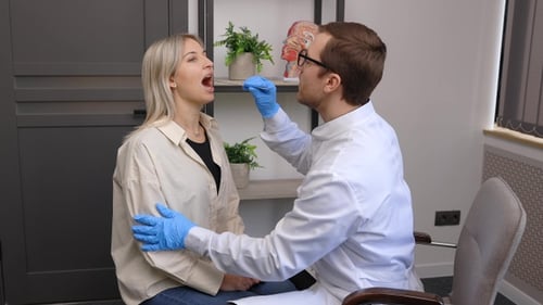 Doctor Examines Woman Patient Throat in Office