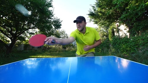 Man with cap plays table tennis outdoors
