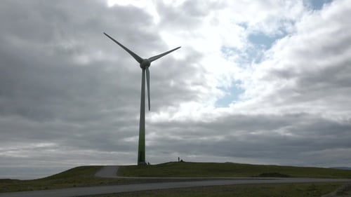 Wind Turbine on Grassy Hillside under Cloudy Sky