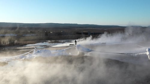 Geyser erupts in Iceland's geothermal landscape during a clear afternoon.