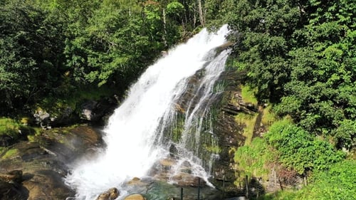 A breathtaking waterfall cascades down rocky cliffs surrounded by lush greenery